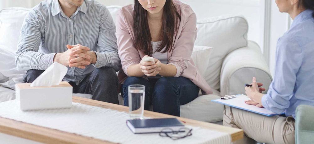 couple discussing opioid rehab in Massachusetts with therapist using clipboard